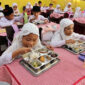 Siswa menyantap makan bergizi gratis di Sekolah Madrasah Ibtidaiyah Negeri Medan, Sumatera Utara, Rabu (14/1/2026).
