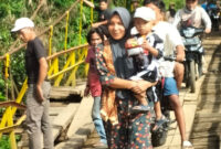 Seorang ibu menggendong anaknya saat melintas di jembatan gantung Desa Talang Buai, Kabupaten Mukomuko, Bengkulu.(Asril)
