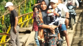 Seorang ibu menggendong anaknya saat melintas di jembatan gantung Desa Talang Buai, Kabupaten Mukomuko, Bengkulu.(Asril)

