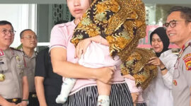Femi (27) memeluk anak kandung perempuannya yang berusia delapan bulan di Mapolda Jambi, Rabu (29/7/2026). Sang bayi bisa kembali setelah dijual ayah kandungnya, Tedi (27). (TRIBUN JAMBI/RIFANI HALIM)
