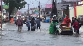 Warga mendorong sepeda motor yang mogok saat melintasi banjir di kawasan Lubuk Lintah,Kuranji Kota Padang, Senin (3/8/2026).(Rahmat Panji (Kompas.com))
