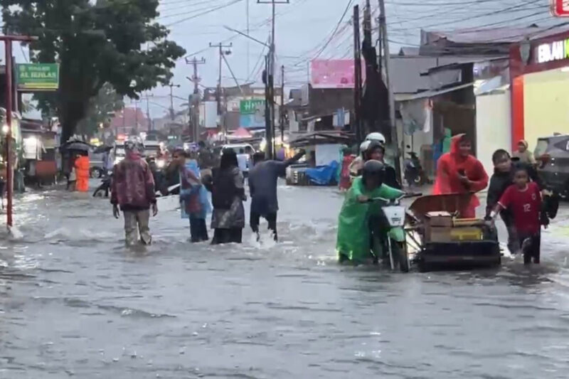 Warga mendorong sepeda motor yang mogok saat melintasi banjir di kawasan Lubuk Lintah,Kuranji Kota Padang, Senin (3/8/2026).(Rahmat Panji (Kompas.com))
