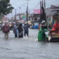 Warga mendorong sepeda motor yang mogok saat melintasi banjir di kawasan Lubuk Lintah,Kuranji Kota Padang, Senin (3/8/2026).(Rahmat Panji (Kompas.com))
