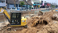 Alat berat bekerja meratakan lahan dan mengeluarkan tunggul pohon pinus setelah pohon berusia puluhan tahun ditebang untuk revitalisasi taman depan Kantor DPRD Kota Bukittinggi, Jumat (04/09/2026).(KOMPAS.COM/DHARMA HARISA)
