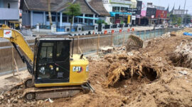 Alat berat bekerja meratakan lahan dan mengeluarkan tunggul pohon pinus setelah pohon berusia puluhan tahun ditebang untuk revitalisasi taman depan Kantor DPRD Kota Bukittinggi, Jumat (04/09/2026).(KOMPAS.COM/DHARMA HARISA)
