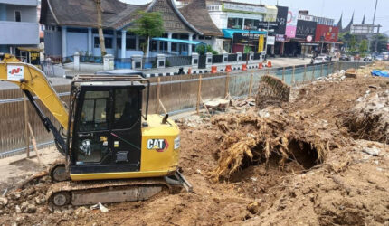 Alat berat bekerja meratakan lahan dan mengeluarkan tunggul pohon pinus setelah pohon berusia puluhan tahun ditebang untuk revitalisasi taman depan Kantor DPRD Kota Bukittinggi, Jumat (04/09/2026).(KOMPAS.COM/DHARMA HARISA)