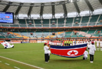Pemain tim nasional sepak bola putri Korea Utara (kanan) dan Korea Selatan (kiri) saat mendengarkan lagu kebangsaan masing-masing negara di babak penyisihan Grup F Asian Games 2026 di Shizuoka Stadium Ecopa, Fukuroi, Prefektur Shizuoka, Jepang, 21 September 2026. (JIJI PRESS via AFP)

