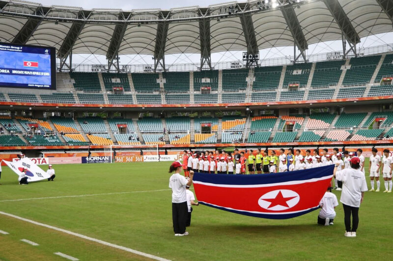 Pemain tim nasional sepak bola putri Korea Utara (kanan) dan Korea Selatan (kiri) saat mendengarkan lagu kebangsaan masing-masing negara di babak penyisihan Grup F Asian Games 2026 di Shizuoka Stadium Ecopa, Fukuroi, Prefektur Shizuoka, Jepang, 21 September 2026. (JIJI PRESS via AFP)

