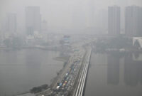 Bangunan-bangunan di seberang jalan penghubung (causeway) di Negara Bagian Johor, Malaysia, tampak diselimuti kabut asap, sebagaimana terlihat dari Singapura pada Jumat (16/10/2026).(AFP/ROSLAN RAHMAN)