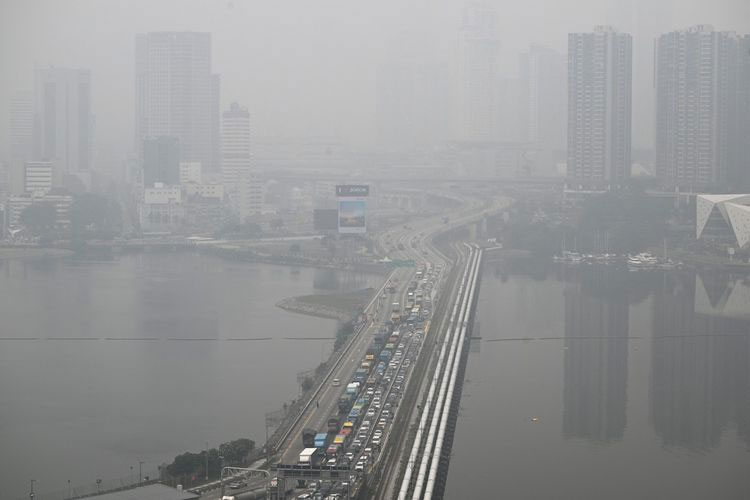Bangunan-bangunan di seberang jalan penghubung (causeway) di Negara Bagian Johor, Malaysia, tampak diselimuti kabut asap, sebagaimana terlihat dari Singapura pada Jumat (16/10/2026).(AFP/ROSLAN RAHMAN)
